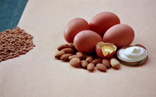 Uova, yogurt greco, legumi e frutta secca su un piano di lino