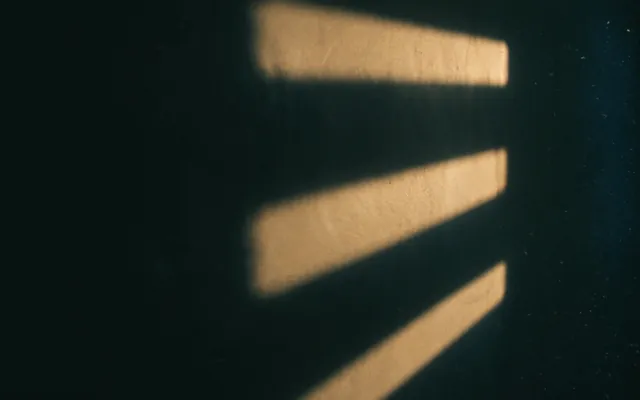 Tre fasci di luce che cadono su un muro intonacato