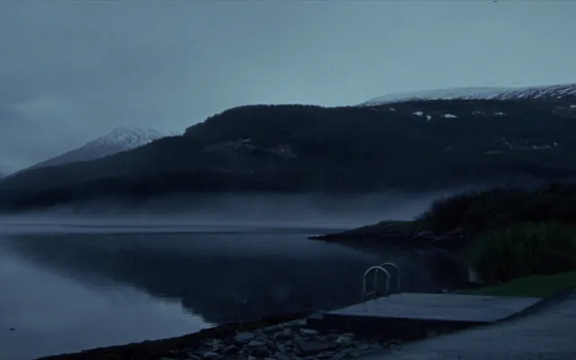 Lago di montagna all'alba con la nebbia che sale dall'acqua